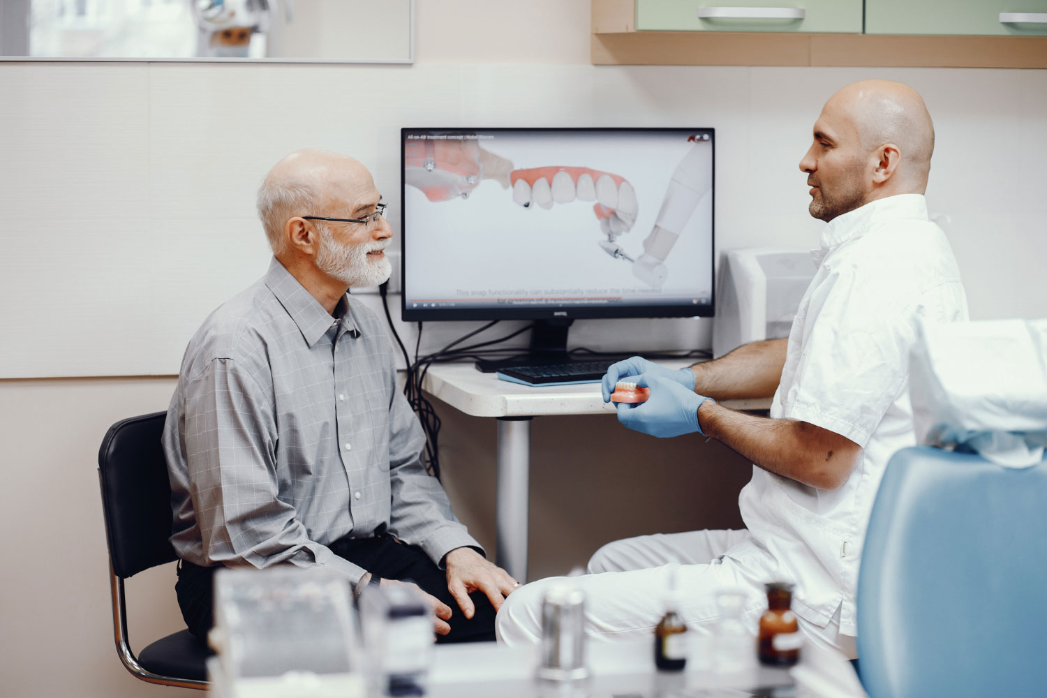 dentist explaining the dental implants procedure to an old man